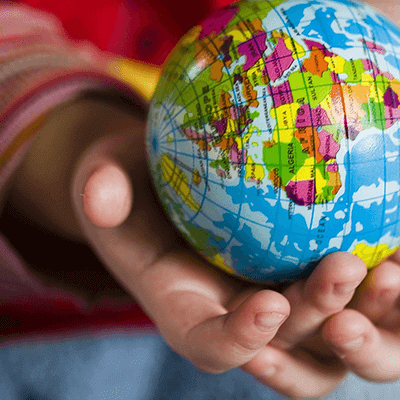 Small child's hands holding toy world globe