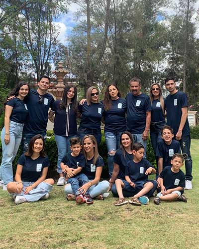 15 members of the Sanchez family, outdoors in a park wearing matching navy blue t-shirts.