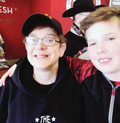 Stephanie White, a young woman with Fragile X syndrome, sitting with a young boy who has his arm around her shoulder.