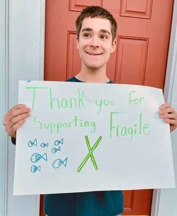 Mitch Chrisoff holding a sign that reads Thank you for supporting Fragile X.