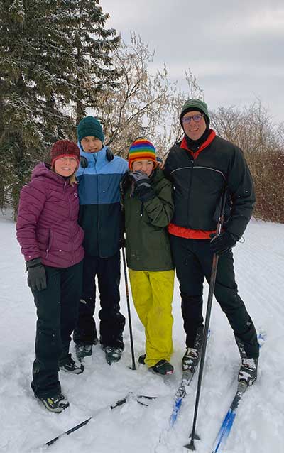 The Weiss Family (Kim, Steve, Tenzin and Elliot) on skis standing on a mountain slope.